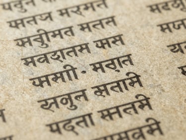 Close-up of ancient textured paper with faded Sanskrit manuscripts, soft diffused library light, archival editorial photography