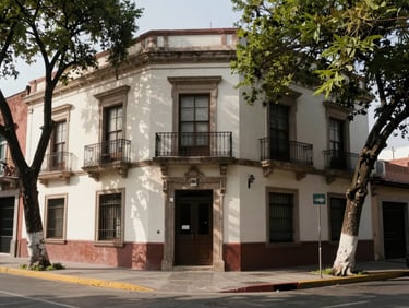 Street-level view of a mixed-use building facade in a Mexican urban neighborhood, mid-day light, clean stucco, pedestrian sidewalk with mature trees