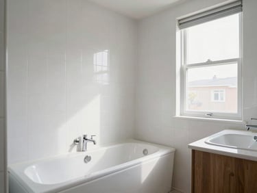 Bathroom interior of a residential property, clean white tiles photographed in natural daylight, wide shot showing tub, vanity, and window, no staging