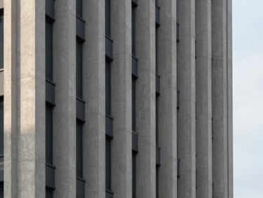 Detail of a modern high-rise concrete facade, sharp geometric shadows, overcast sky