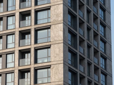 Architectural detail of a modern high-rise development, sharp morning shadows, high-contrast concrete and glass, 35mm architectural lens