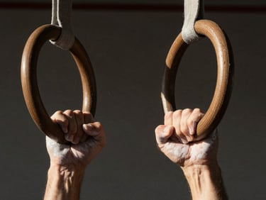 Tight macro crop of chalked hands gripping wooden gymnastics rings, dramatic natural side-lighting, dark minimalist background.