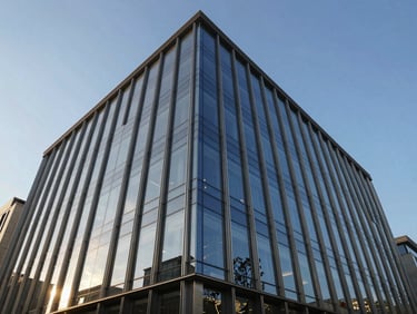 Low-angle architectural perspective of a dramatic commercial glass facade, reflecting a crisp blue sky, sharp metallic lines.