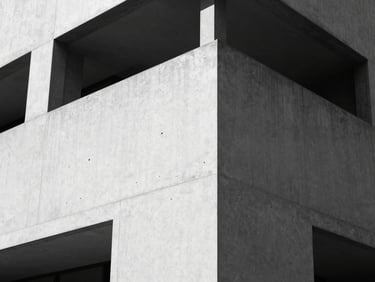 High-contrast black and white photograph of a minimalist concrete building corner, sharp geometric shadows, clean architectural lines, 35mm lens.
