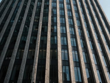 Wide-angle architectural abstraction of a modern skyscraper facade made of glass and concrete, dramatic low-key lighting, cool-toned shadows.