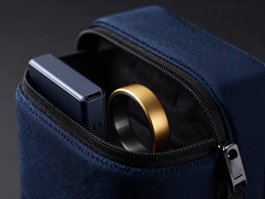 Macro shot of a zero-bloat tech pouch, containing a few essential, high-end gadgets (e.g., smart ring, portable SSD), soft studio shadows, deep navy and gold accents. Sleek editorial photography, moody studio lighting, deep navy and gold accents, sharp macro focus, 35mm.