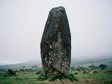 Low-angle shot of a towering ancient stone dolmen in a misty Bondowoso field, overcast highland daylight, deep volcanic stone textures, 35mm film style