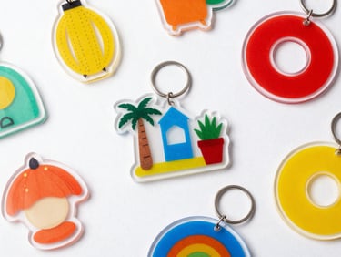 Overhead flat lay of various acrylic home decor items and keychains, showcasing sharp UV printing and glossy finish, studio lighting.