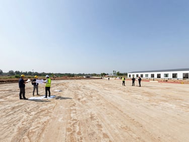 Wide shot of an undeveloped commercial site in natural daylight, surveyors mapping the terrain.