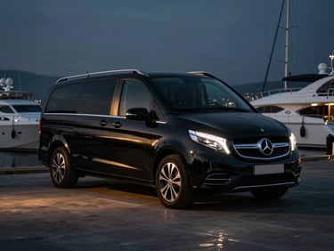 Pristine black Mercedes Vito parked near a luxury yacht marina in Kemer under dramatic low-key evening lighting