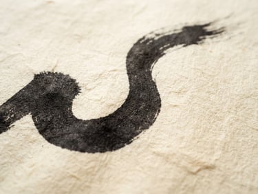 Macro detail of a single bold calligraphic stroke on textured ivory handmade paper, soft natural side-light, minimal composition