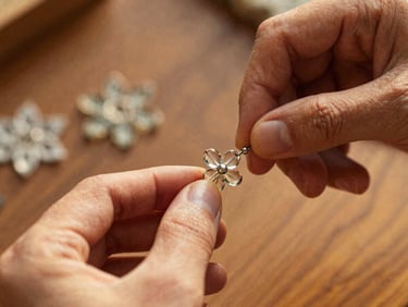 Macro photograph of hands carefully threading tiny glass beads into a complex floral pattern, warm indirect daylight, shallow depth of field.