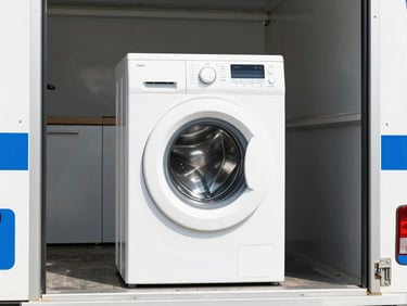 A clean white washing machine and kitchen appliances being loaded onto a branded utility truck, bright midday sun