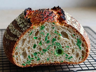 Close-up of a rustic sourdough loaf with a perfect crust, sliced open to show its texture, on a cooling rack.