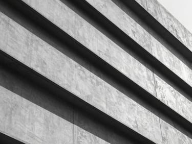 Close-up of structured architectural lines with sharp geometric shadows in cool daylight, high-contrast monochrome.