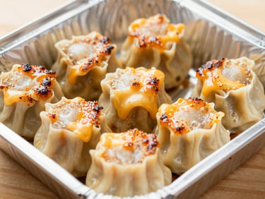 Appetizing close-up of a medium foil box with six pieces of dimsum mentai, bubbling torched sauce, melting cheese on top, macro shot