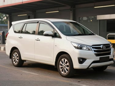 Three-quarter front of a white Toyota Innova parked at a Bangalore terminal pickup bay in morning light, sliding door closed, clean exterior