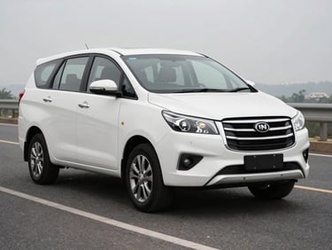 Three-quarter front of a white Innova Crysta on a wide daylit road, premium alloy wheels and grille detail visible, clean paint
