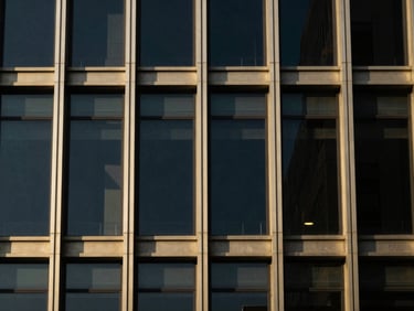 Abstract architectural detail of a glass and steel building, high-contrast, sharp lines, metallic gold reflections, off-center