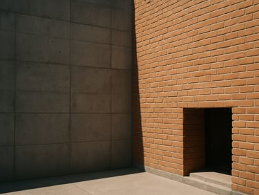 Exterior facade of Casa Materia, raw concrete blocks meeting hand-laid terracotta bricks under high-contrast afternoon sun.