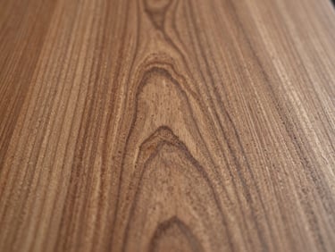 Macro overhead shot of hand-planed cherry wood, showcasing the highly detailed, organic grain patterns and rich natural texture under soft, directional side-light.