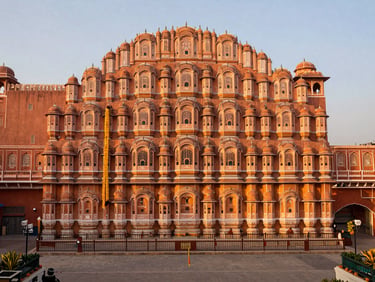 Wide shot of a royal palace courtyard in Jaipur, adorned with marigold garlands, warm evening light, elegant setup for a wedding ceremony.
