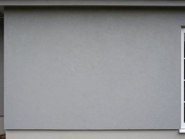 Freshly applied grey stucco foundation cladding on a residential exterior, even texture, clean bottom edge, natural overcast daylight, wide framing