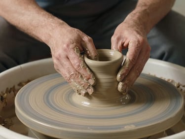Close-up of potter's hands gently shaping a raw clay urn on a spinning wheel, warm natural light highlighting textures of clay and skin.