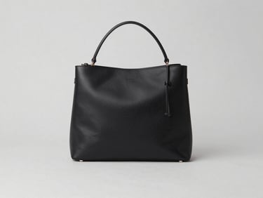 Clean flat-lay of a minimalist black leather bag and accessories on a neutral light gray backdrop, sharp focus