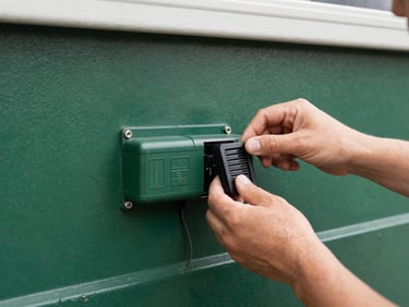 Medium shot of a garage door opener motor unit, clean and well-maintained, with a technician's hand adjusting a sensor, natural garage lighting.