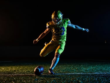 Action shot of a football player striking a ball, dramatic low-key lighting with neon green rim light, dark background, cinematic contrast, 35mm