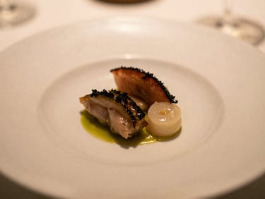 Close-up of a perfectly plated gourmet dish at a Michelin-starred coastal restaurant, elegant presentation, soft golden light, muted tones, shallow depth of field, 35mm film style