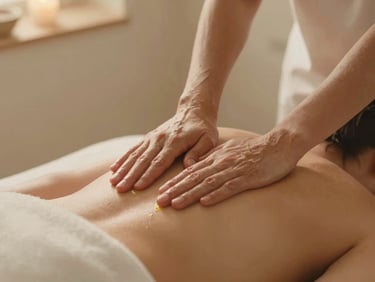 Close-up of hands applying warm, natural oils during a massage in a quiet, minimalist spa treatment room, soft, diffused light, natural textures. warm editorial photography, soft golden-hour light, muted beige and alabaster tones, shallow depth of field, 35mm film style.