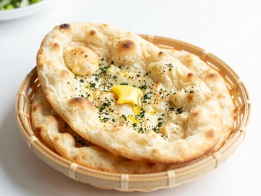 Bright high-key food photography, soft natural daylight, fluffy garlic naan stacked on a light woven basket, glistening garlic butter