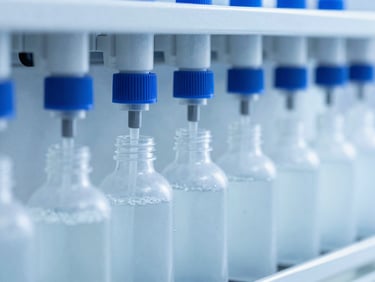 Automated pharmaceutical bottling line filling clear syrup bottles, sterile cool blue and white tones, bright high-key laboratory lighting, sharp macro focus, 35mm