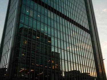 Sleek glass and steel commercial high-rise facade at twilight, deep emerald reflections, modern architectural lines, 35mm.