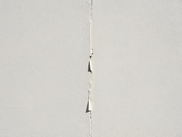 Straight-on architectural detail of a perfectly painted wall junction, crisp tape line being peeled back to reveal a razor-sharp edge, bright natural daylight, zero dust.