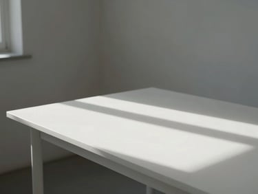 Minimalist studio workspace with natural light streaming across a clean white table, architectural details showing scale and light.