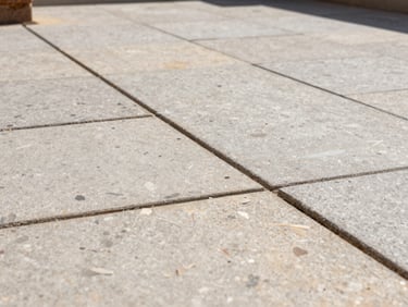 Close-up of a clean, newly laid stone paving joint on a residential terrace, bright natural daylight highlighting the precise mineral texture and clean lines.