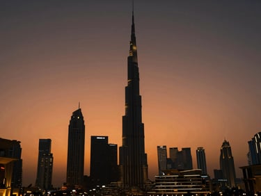 Modern Dubai skyline at dusk, dramatic orange and deep charcoal sky, architectural silhouette, luxury lifestyle aesthetic.