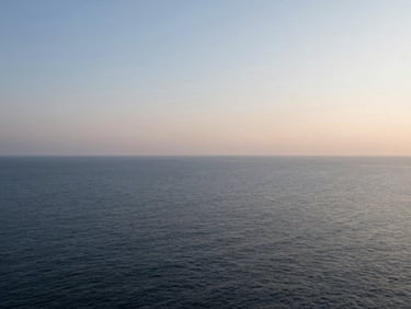 An open horizon over a calm ocean at dawn, minimalist composition, soft diffused daylight.
