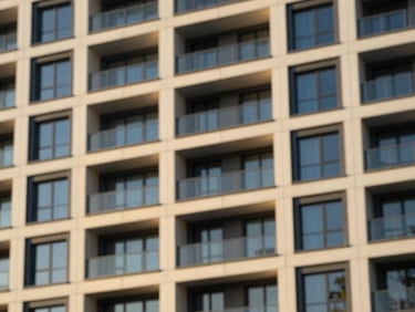 Clean geometric facade of a modern multi-family residential building, crisp morning sunlight, architectural photography, warm gold accents, tilt-shift lens.