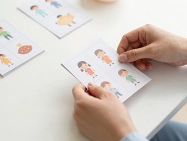 Hands of a therapist neatly organizing printed social story cards with simple illustrations on a clean white table, warm soft lighting