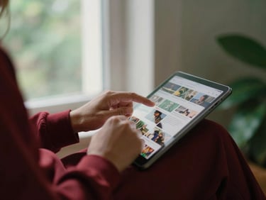 Hands editing social media content on a tablet, soft natural window light, rich crimson and forest green tones, shallow depth of field, 35mm