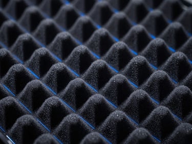 Macro photography of high-tech acoustic dampening foam and metallic panels, deep blacks, neon blue accent lighting.