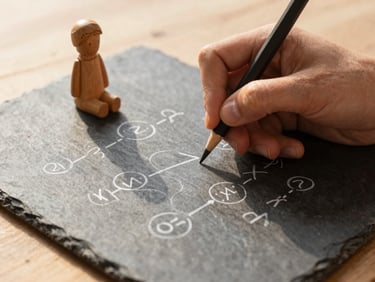 Close-up of hands solving a math problem on a slate tablet, a small wooden figurine of a child beside it, natural light, warm editorial photography