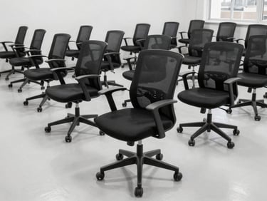 Dozens of black ergonomic office chairs lined up on a clean empty commercial floor, daylight, 35mm lens