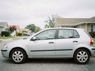A car parked on a quiet residential street during overcast daylight, soft focus background, clean and realistic everyday scene, 35mm lens.