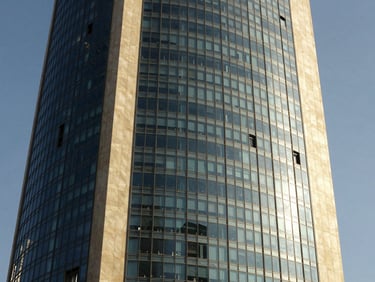 Crisp daytime architectural shot of the KAFD tower in Riyadh, high-contrast shadows, premium glass and steel facade.