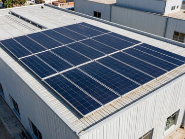 Architectural shot of a 10kW solar array on a commercial building rooftop in Pakistan, high-contrast, deep blue panels.